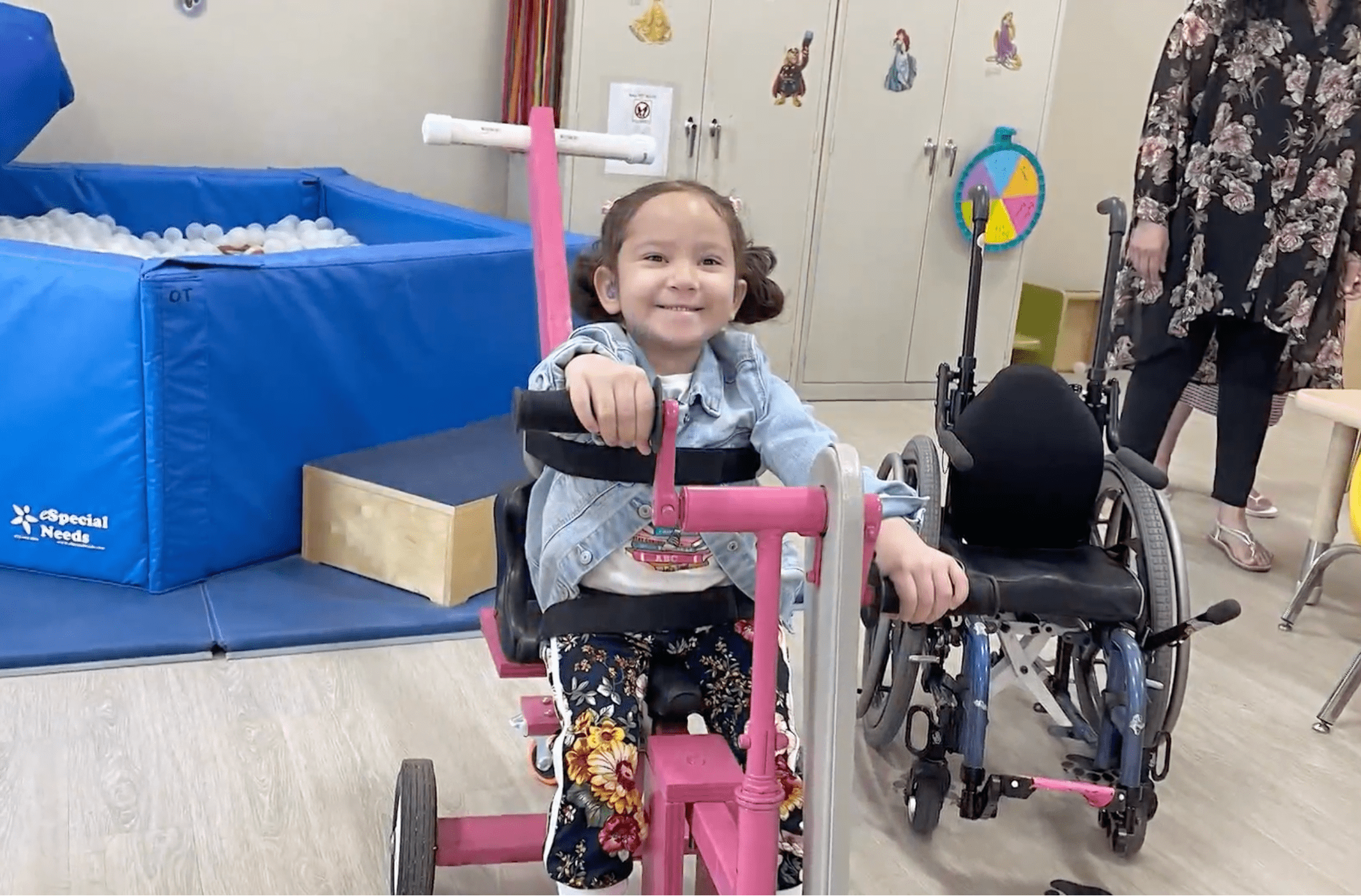 A preschooler riding a tricycle in a class