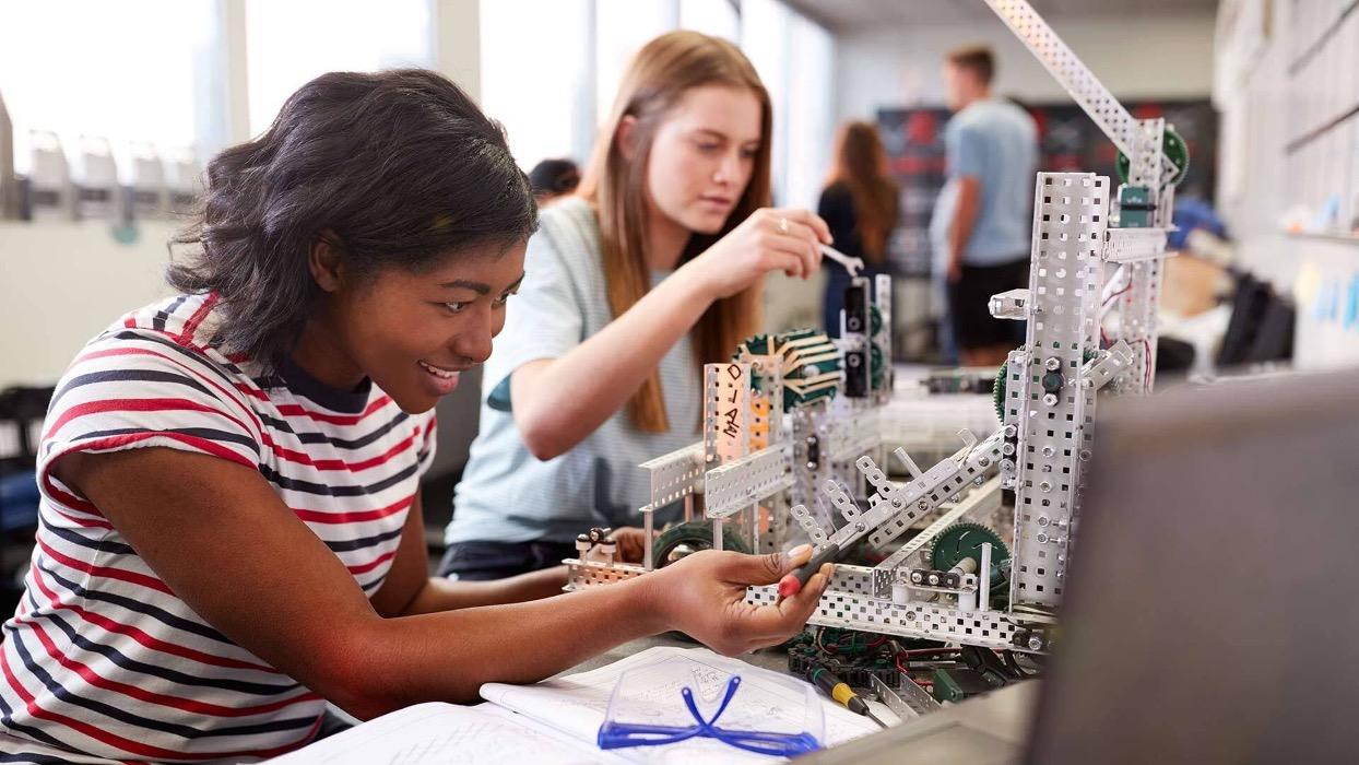 Decorative image of two students constructing a structure of a project