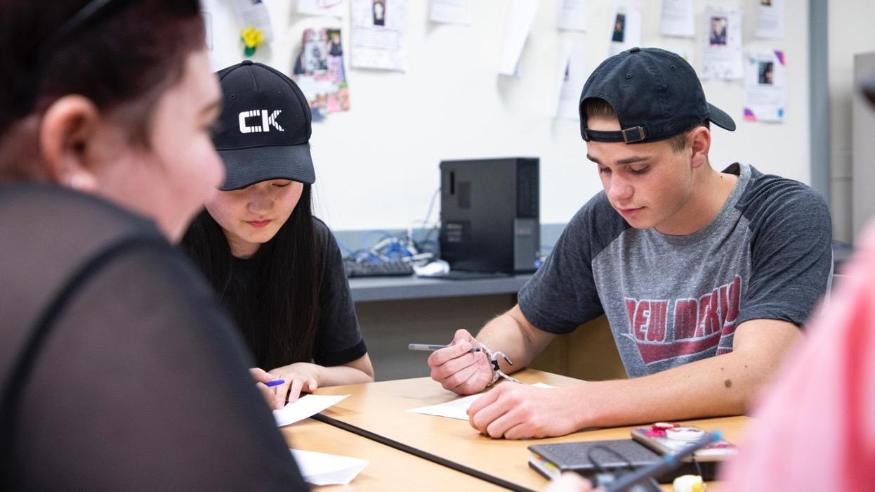 Three students around a table in the classroom