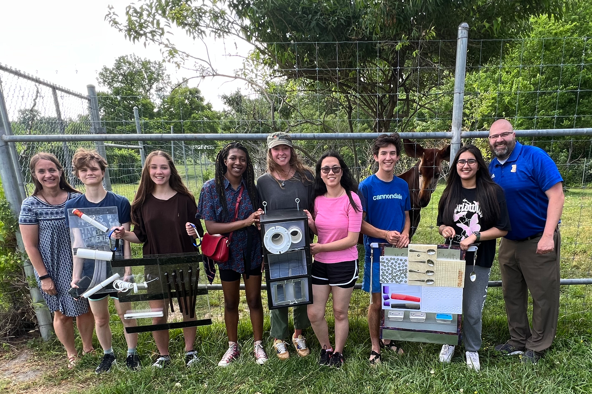 Six of e4usa students and three teachers holding their projects infront of the zebra cage at the zoo.